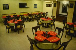a dining room with tables and chairs with red napkins at Hotel Aditya in Raipur