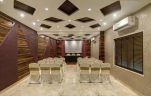 a conference room with white chairs and a stage at Hotel Aditya in Raipur
