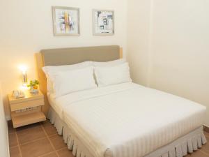 a bedroom with a white bed with a night stand at d'primahotel Airport Jakarta Terminal 1A in Tangerang