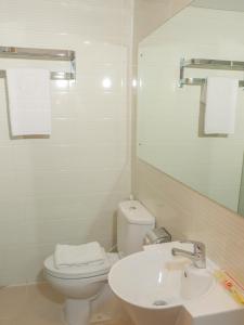 a bathroom with a toilet and a sink and a mirror at d'primahotel Airport Jakarta Terminal 1A in Tangerang