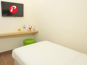 a bedroom with a white bed and a green chair at d'primahotel Airport Jakarta Terminal 1A in Tangerang