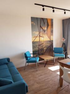 un soggiorno con divano blu e sedie di Fok Sztormowy a Hel