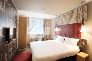 a hotel room with a large bed and a tv at Ibis Gdansk Stare Miasto in Gdańsk