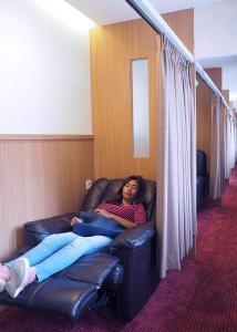 a woman laying on a leather couch in a room at d'primahotel Airport Jakarta Terminal 1A in Tangerang