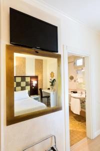 a bathroom with a large mirror and a television at iH Hotels Logos Forte Dei Marmi in Forte dei Marmi