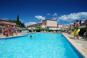 un grupo de personas de pie alrededor de una piscina en Lagrange Grand Bleu Vacances – Résidence Les Jardins de Neptune, en Saint-Cyprien