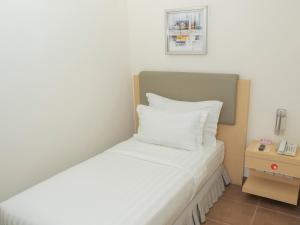 a small bedroom with a bed with white sheets at d'primahotel Airport Jakarta Terminal 1A in Tangerang