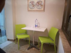 stół i 2 zielone krzesła w pokoju w obiekcie SEGESTA - Le Bouquet w mieście Salemi