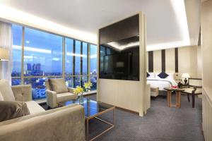 a living room with a couch and a bed and a television at ASTON Kartika Grogol Hotel & Conference Center in Jakarta