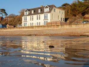 a house on the beach with its reflection in the water at Promenade Apartment with own Beach Hut in Totland
