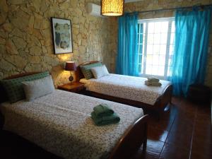 a bedroom with two beds and a window with blue curtains at Casa da Ribeira (Sesimbra) in Sesimbra