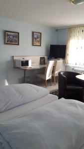a bedroom with two beds and a desk and a table at Hotel Restaurant Anna in Ramstein-Miesenbach