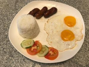 un plato de comida con huevos, arroz y tomates en Babylon Oslob Coast Guesthouse, en Oslob
