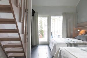 a bedroom with two beds and a staircase with a window at Varjola Holiday Center in Laukaa