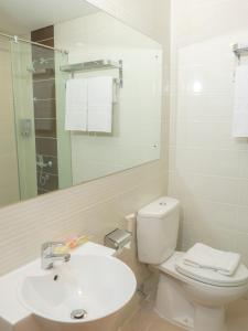 a white bathroom with a toilet and a sink at d'primahotel Airport Jakarta Terminal 1A in Tangerang