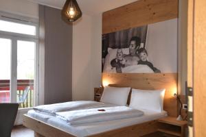 a bedroom with a bed with a picture on the wall at Angerburg Blumenhotel in Appiano sulla Strada del Vino