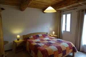 a bedroom with a bed with a colorful quilt at Gîtes Les Costoliers in Châteauneuf-Miravail +40 photos