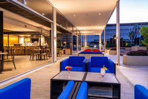 eine Terrasse mit blauen Stühlen und einem Tisch auf einem Gebäude in der Unterkunft ONOMO Hotel Durban in Durban