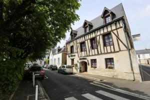 a building on a street with cars parked on the street at Hôtel Le Blason in Amboise