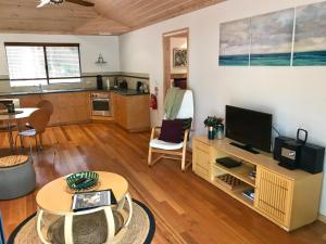 a living room with a television and a kitchen at Ellensbrook Cottages in Cowaramup