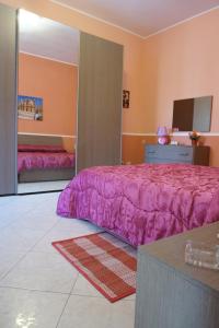een slaapkamer met een paars bed en een televisie bij Casa Vacanza il Ciliegio in Noto