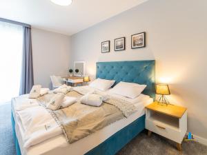 a bedroom with a large bed with a blue headboard at 3L Apartments Aquarius in Kołobrzeg