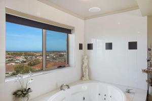a white bathroom with a tub and a window at Comfort Inn On Raglan in Warrnambool +79 photos