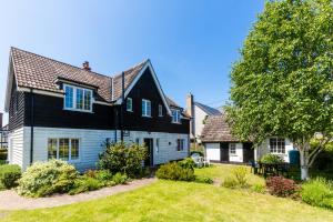 ein Schwarz-Weiß-Haus mit Garten in der Unterkunft Lake Cottage - A large holiday home in Thorpeness - Close to the beach and The Meare - Aldeburgh Coastal Cottages in Thorpeness