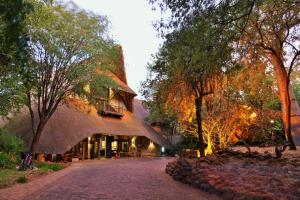 a building with a thatched roof with a tree at Victoria Falls Safari Lodge in Victoria Falls