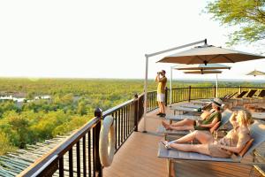 a group of people sitting on the deck of a resort at Victoria Falls Safari Lodge in Victoria Falls