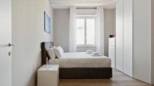 a white bedroom with a bed and a window at Italianway - Largo Allegri 4 in Milan