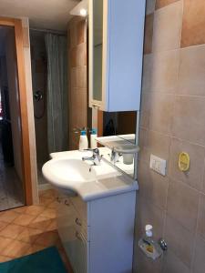 y baño con lavabo blanco y espejo. en Appartamento Dalma Foresta, en Lavarone