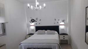Habitación blanca con cama y lámpara de araña. en VuT San Blas, en Ciudad Rodrigo