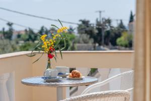 einen Tisch mit einer Vase Blumen und einem Teller Essen in der Unterkunft Mimoza in Spetses