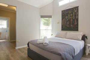 a bedroom with a large bed with a painting on the wall at Atticus Cottage in Bright