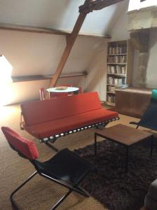 
a red couch sitting in a living room next to a chair at Manoir de la Guerrie in Saint-Patrice-de-Claids
