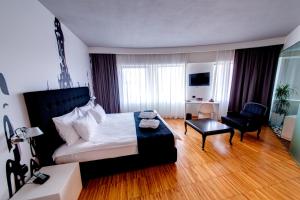 um quarto com uma cama, uma cadeira e um sofá em Sarroglia Hotel em Bucareste