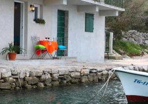 a table and chairs sitting outside of a house next to the water at Pearl in Drvenik Veli