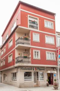 a red building with balconies on a street at Hospedaxe Maria Aguiño in O Grove