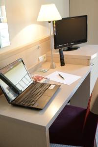 un ordenador portátil sentado en un escritorio con monitor en Hotel Restaurant Rolland en Montagnieu