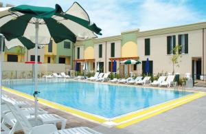 a swimming pool with chairs and an umbrella at Farnie Lido Altanea in Caorle