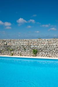 un mur en pierre à côté d'une piscine bleue dans l'établissement Agriturismo Masseria Alcorico, à Gagliano del Capo