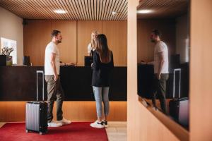 Kobieta i dwóch mężczyzn stojących w biurze w obiekcie Hotel Hubertus Mellau GmbH w mieście Mellau