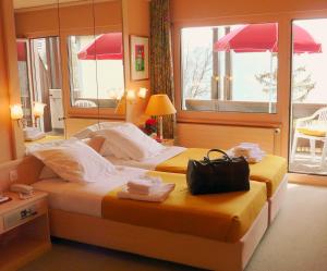 Hôtel de la Forêt في كرانس مونتانا: غرفة في الفندق سرير وعليها شنطة