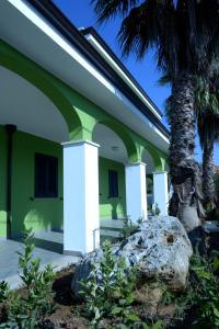 a green and white building with a palm tree at Villa Sofia in Porto Cesareo