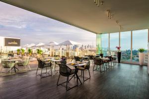 un restaurant avec des tables et des chaises et une vue sur la ville dans l'établissement The Canvas Dubai - MGallery Hotel Collection, à Dubaï