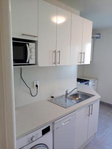 a kitchen with white cabinets and a sink and a microwave at Apartmány Karviná in Karviná