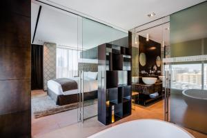 a bedroom with a bed and a bathroom with a sink at The Canvas Dubai - MGallery Hotel Collection in Dubai