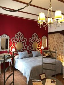 um quarto com uma cama e uma parede vermelha em Retiro del Teatro Almagro em Almagro
