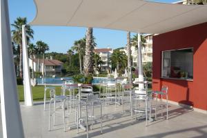 a patio with chairs and tables and a pool at HG Jardín de Menorca in Son Bou